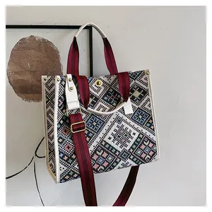 Detail of colorful geometric woven pattern on a spacious canvas tote with red striped straps