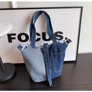 Detail of a denim bucket bag with dual-tone blue patchwork design and side pocket