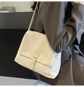 Detail view of the cream white retro messenger bag worn on the shoulder by a model