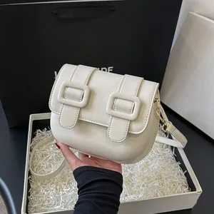 Minimalist beige crossbody saddle bag with dual flap and square buckle detail