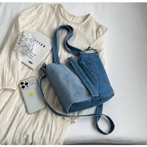 Top view of patchwork denim bucket bag with metal ring detail on cream pleated fabric