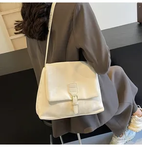 Detail showing white leather satchel bag with flap closure and adjustable metal buckle strap