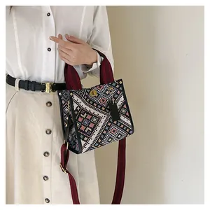 Detail of bohemian woven pattern on tote bag with red shoulder strap and gold clasp