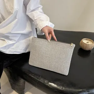 Gros plan d'une pochette en tissu gris avec fermeture éclair dorée et design minimaliste