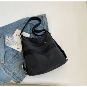 Detailed flat lay of black canvas tote with zipper pocket and wide adjustable strap