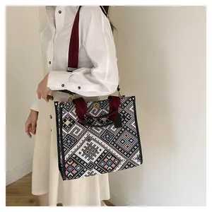 Detail of a large ethnic embroidered tote bag with geometric patterns on a female model