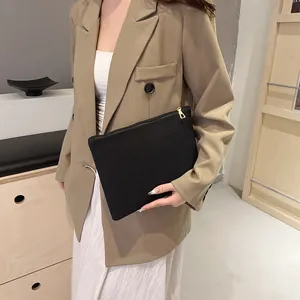 Pochette chic en lin noir avec fermeture dorée portée par un mannequin en tenue élégante