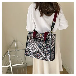 Detail of geometric pattern tote bag with wide straps and golden metal rotary buckle