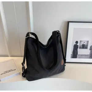 Detail of black canvas tote bag showing thick texture and round leather logo patch