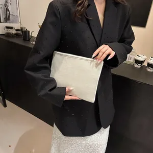 Pochette chic en toile crème montrée avec une tenue moderne et une texture de tissu premium