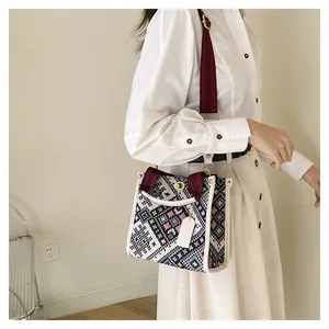 Detail of colorful geometric woven pattern with white leather trim and metal rotary lock