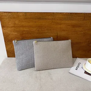 Détail de pochettes en lin gris et beige avec fermeture éclair sur fond en bois