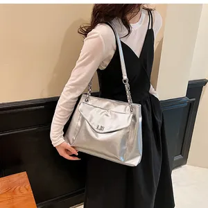 Detail of silver metallic tote bag featuring chain strap and envelope flap closure