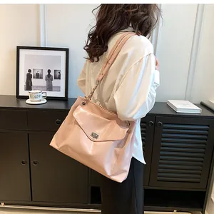 Detail of pink faux leather tote bag with silver metal twist lock and chain strap design