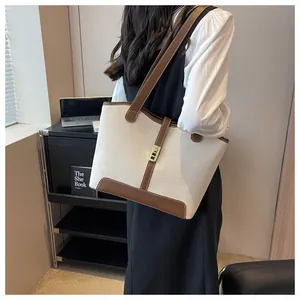 Detail of canvas tote bag with brown leather trim and golden metal swivel lock