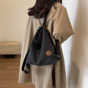 Black canvas tote bag with brown leather patch, shown as a casual shoulder bag style