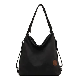 Large black canvas tote bag with adjustable side straps and brown leather logo detail