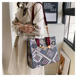Detail of ethnic woven tote bag with geometric patterns and red fabric strap