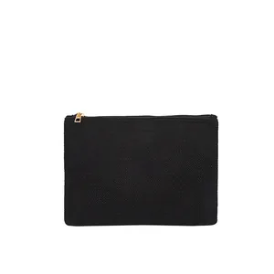 Détail de pochette en toile noire avec fermeture éclair dorée et texture tissée mate