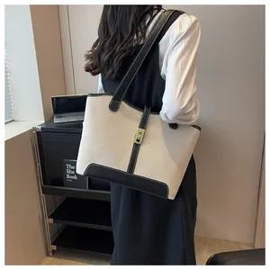 Detail of contrast canvas tote bag with black leather trim and gold metal lock buckle