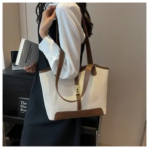 Detail of canvas tote bag with brown leather trim and golden metal clasp closure
