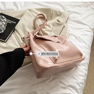 Side view of pale pink patent leather tote bag with metal lock and rivet shoulder strap