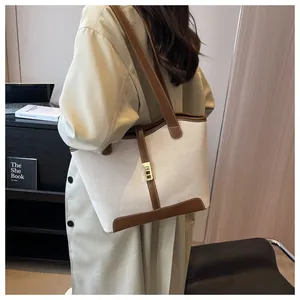 Detailed view of canvas tote bag with brown leather trim and golden metal buckle on model