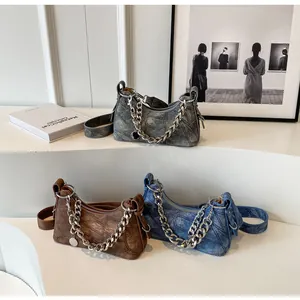 Detailed view of denim patchwork bags in grey, blue, and brown with metallic chains