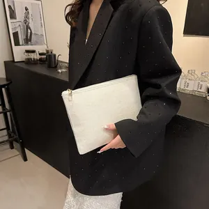 Pochette chic en lin blanc avec fermeture éclair dorée tenue par un mannequin élégant