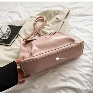 Detailed view of the structured flat bottom and stitching on a pink faux leather tote