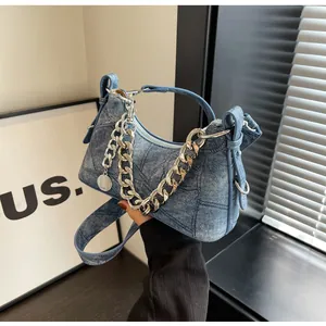 Detail of blue denim hobo bag with vintage wash texture and silver metal chain strap