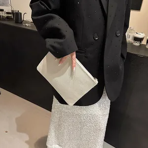 Pochette chic en lin beige avec fermeture éclair en métal dans un café élégant