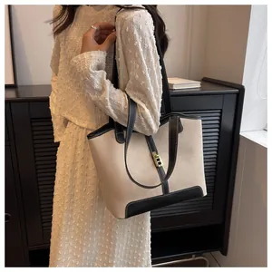 Detail of canvas tote bag with black leather trim and golden twist lock on white dress
