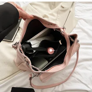 Detail view of pink glossy tote bag with silver chain strap and spacious inner pockets
