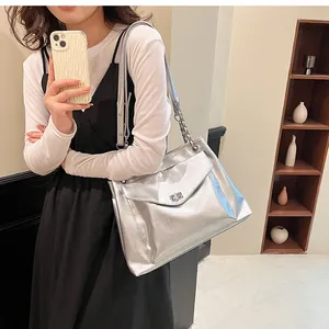 Silver metallic tote bag with chain strap and twist lock shown on model for size reference