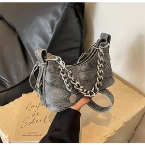 Detail of grey denim texture handbag with chunky silver chain and round metal pendant