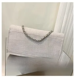 Détail de la texture en tweed tissé et de la bandoulière chaîne du sac seau écru
