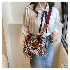 Detail of geometric ethnic woven tote bag featuring leather handles and metal twist lock