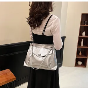 Silver metallic tote bag with turn-lock clasp detail shown on a model's shoulder