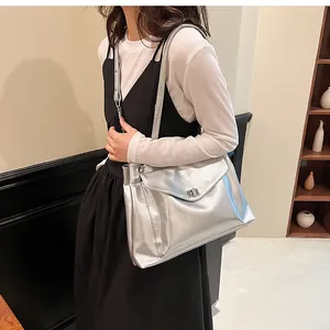 Detail of silver metallic shoulder bag with turn-lock closure and glossy pleated texture