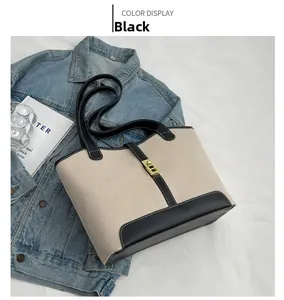 Detail of canvas tote with black leather trim, stitching and gold metal twist lock