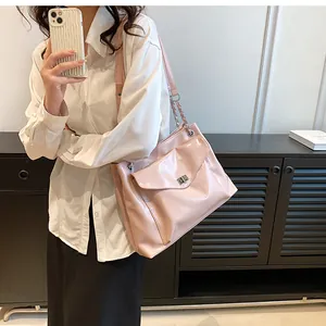 Detail of pink patent leather shoulder bag featuring silver metal lock and chain strap