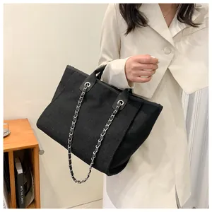 Détail du sac cabas en toile noire avec chaîne en métal entrelacée de cuir chic