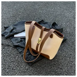 Detail of canvas tote bag with brown leather trim and golden metal lock on leather jacket