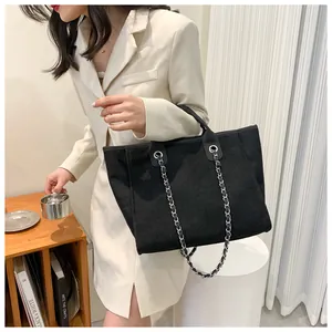 Détail du cabas en toile noire avec doubles poignées et bandoulière en chaîne