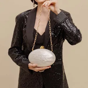 Close-up of cream white marble texture acrylic evening clutch with gold chain strap