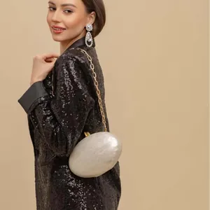 Macro detail of oval pearl finish evening clutch with elegant gold chain strap
