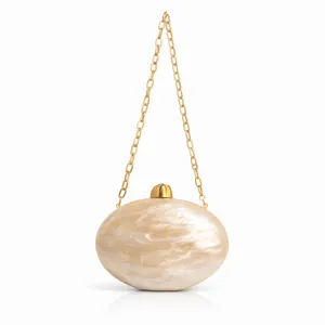Close-up of semi-circle evening clutch bag with pearl texture and golden chain