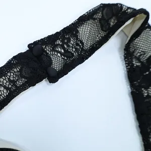 Detailed view of black lace patterns and matching fabric buttons on dress neckline
