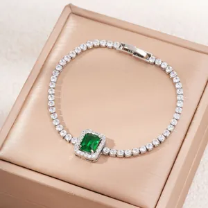 Detail of emerald cut green zircon bracelet with shimmering pavé stones on champagne satin